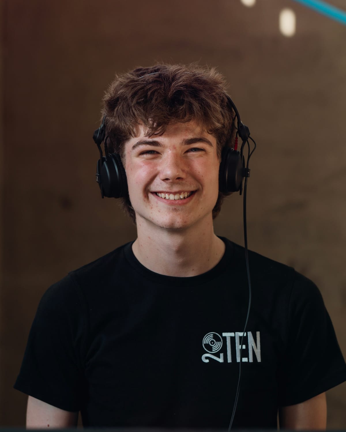 Charlie from 20TEN DJ smiling in headphones and a 20TEN T-shirt